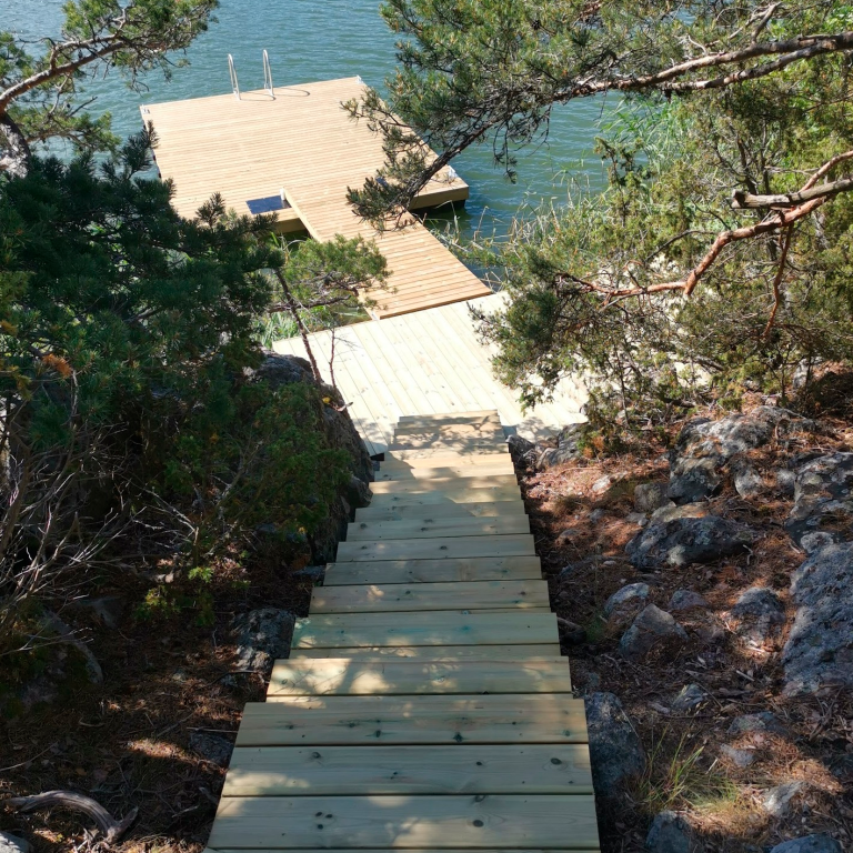 Jyrkkään maastoon rakennettu laituri ja rappuset veden äärelle